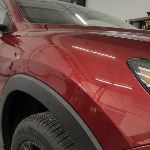 Sharp dent on a red SUV's fender — smoothed back to a flawless factory finish with paintless dent repair. — after