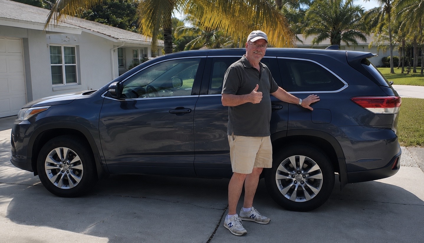 Happy Dents Now customer giving a thumbs up next to his blue Toyota Highlander