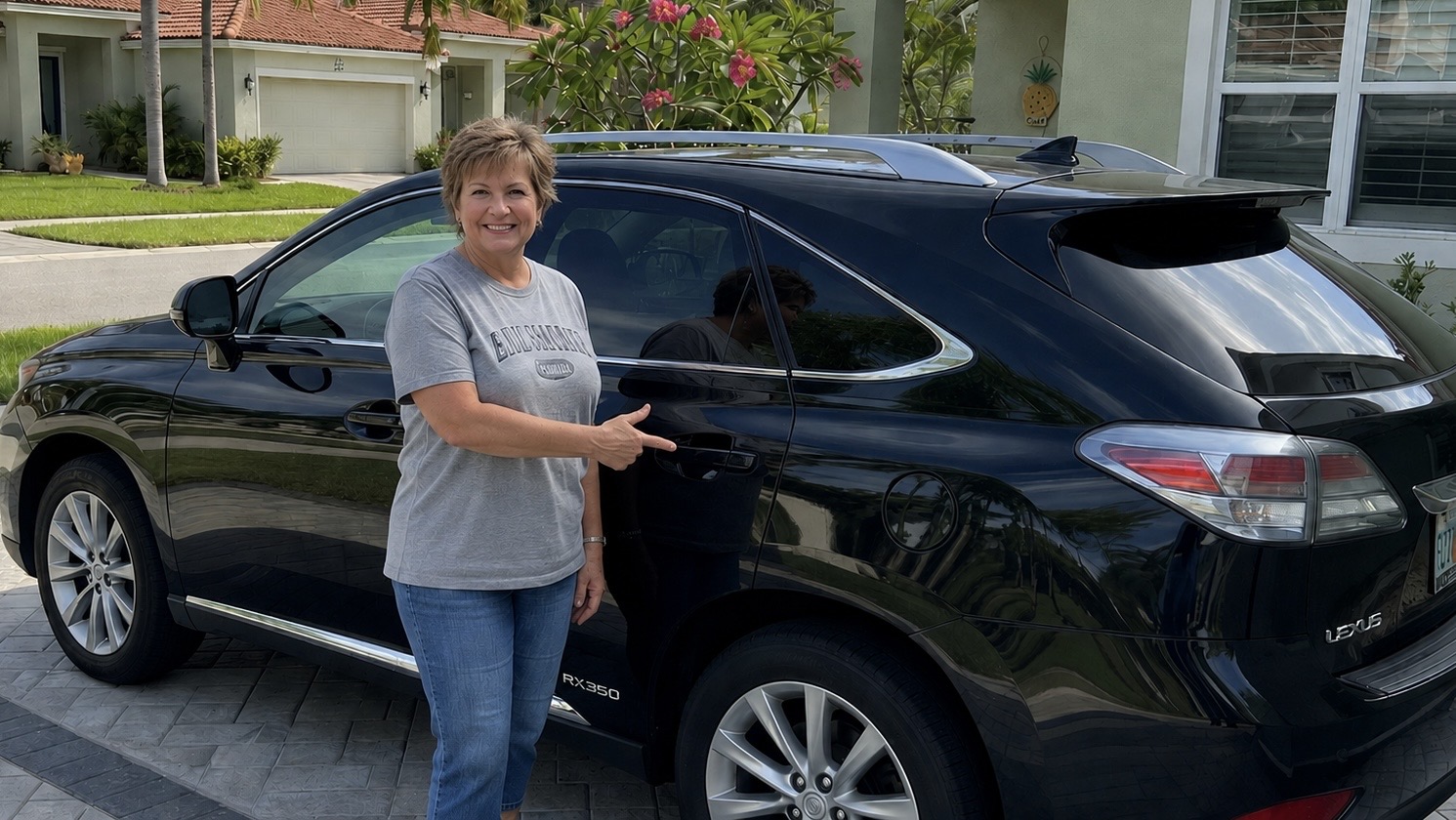 Happy Dents Now customer giving a thumbs up next to her black Lexus RX350