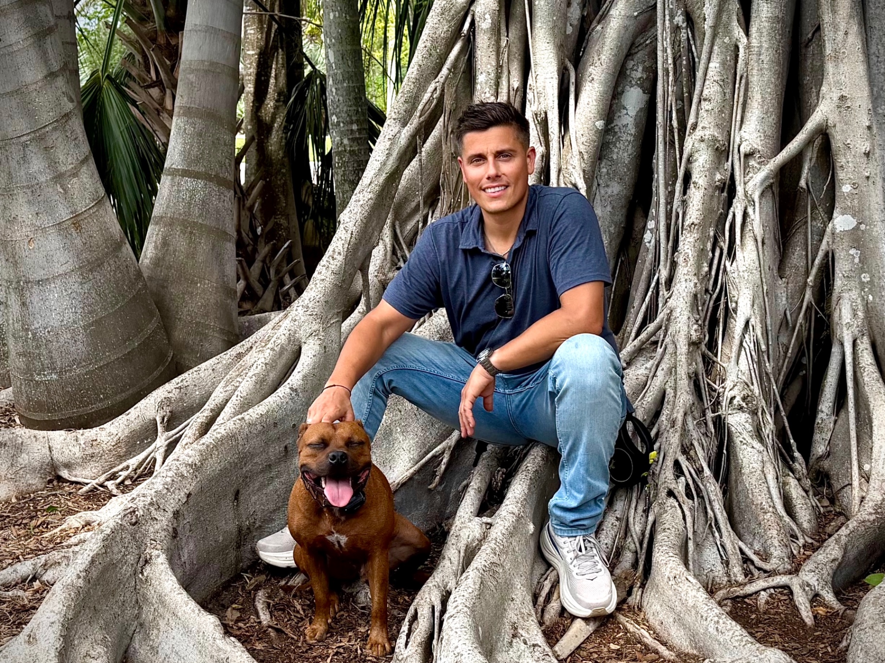Michael Mezzano sitting on tree roots with his dog — local Sarasota owner-operator